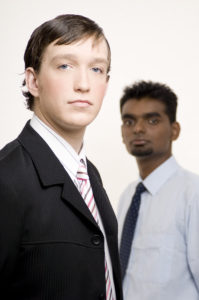 A smart caucasian businessman in a suit (in focus) with another businessman behind (out of focus)